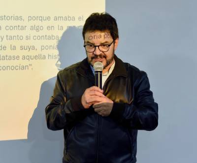 Ruben Dario Buitron vestido con chaqueta oscura sostiene un micrófono entre sus manos
