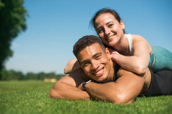 Pareja relajándose sobre el césped en un parque, representando un estilo de vida saludable y activo al aire libre.