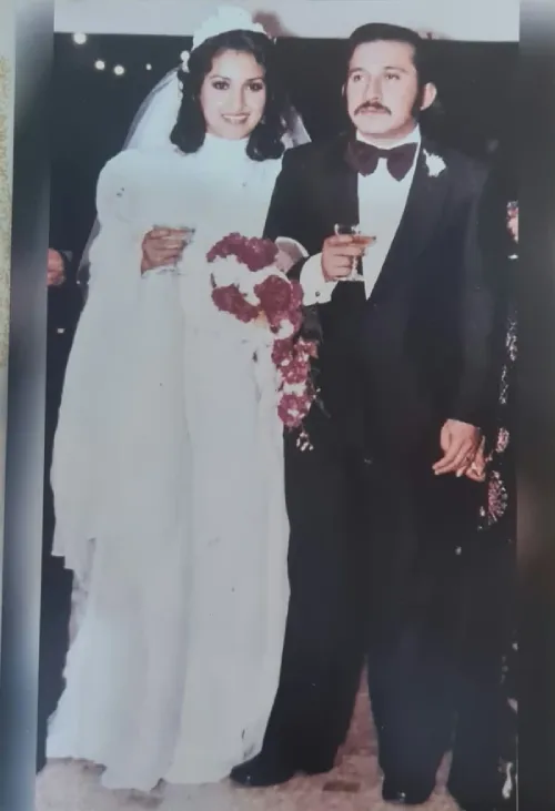 Fotografía de bodas de Carmen Zea y Amalio Martínez: la novia vestida de blanco con velo y ramo, y el novio con esmoquin negro y corbata de moño, ambos brindando con copas.