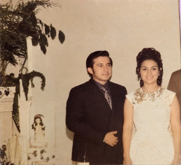 Fotografía vintage de Carmen Zea y Amalio Martinez posando juntos en la fiesta de 15 años de ella. Carmen viste de blanco con tiara y Amalio lleva traje oscuro.